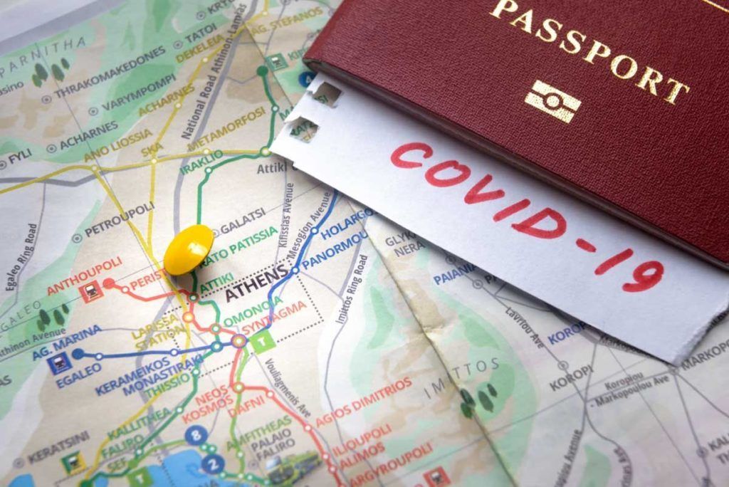 Travel and COVID-19 coronavirus in Greece, Europe. COVID mark in tourist passport on map with Athens. Tourism hit by corona virus. Medical test at border control due to coronavirus pandemic.