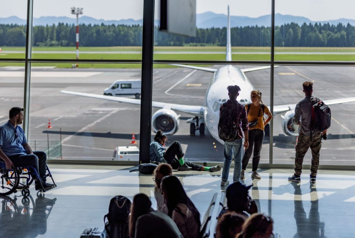 Bustling airport terminal with a glimpse of the runway. Credit: Azman Jaka, iStock